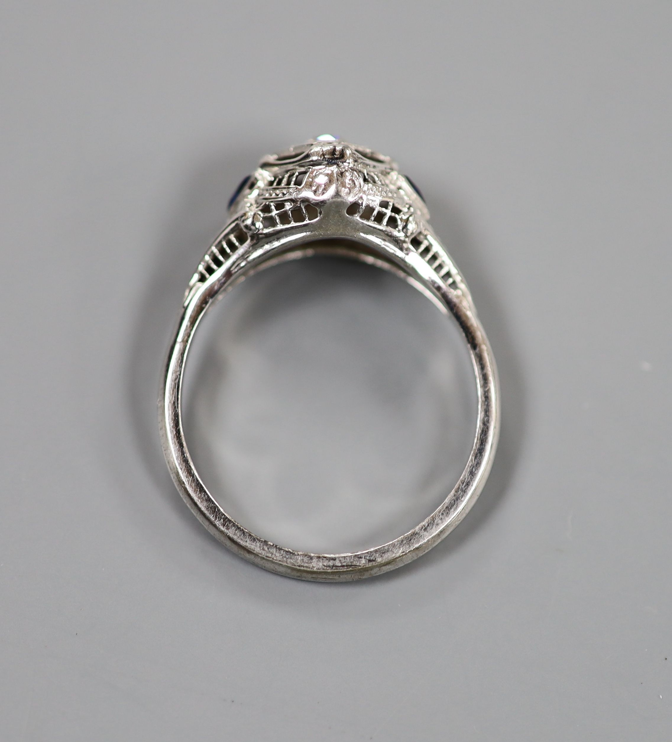 A 18ct white metal and single stone diamond ring, with triangular cut blue stone set shoulders, size P, gross weight 3.2 grams.